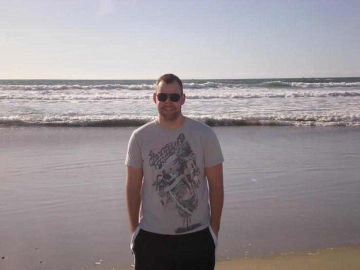 a man is standing on the shore near a wave