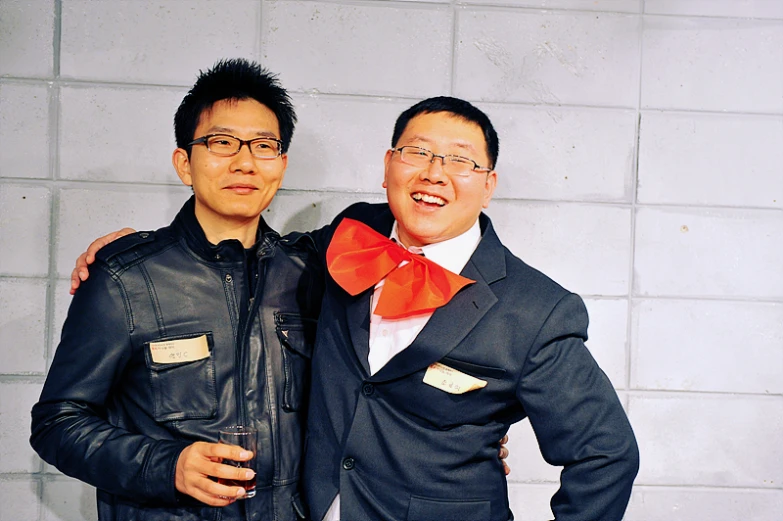 two men wearing black coats and orange bow ties standing next to each other