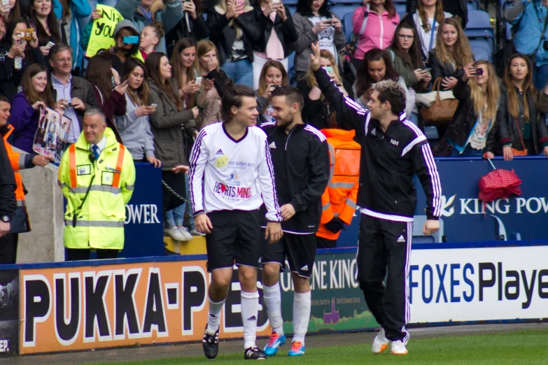 players from both teams react to a goal in front of the crowd