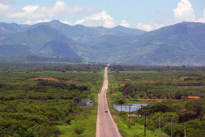 a road with some trees and hills in the distance