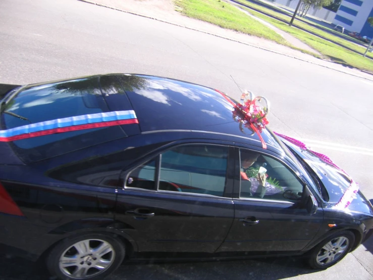 a small black car with an order of flowers on the back of the car