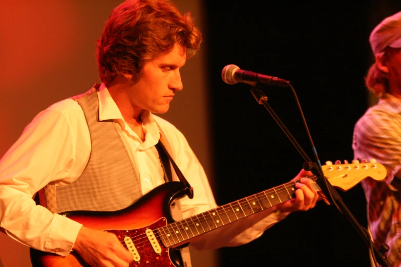 a man playing an electric guitar near a microphone