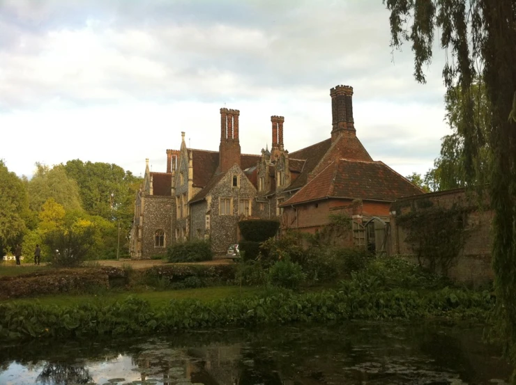 an old building with brick chimneys is near a pond