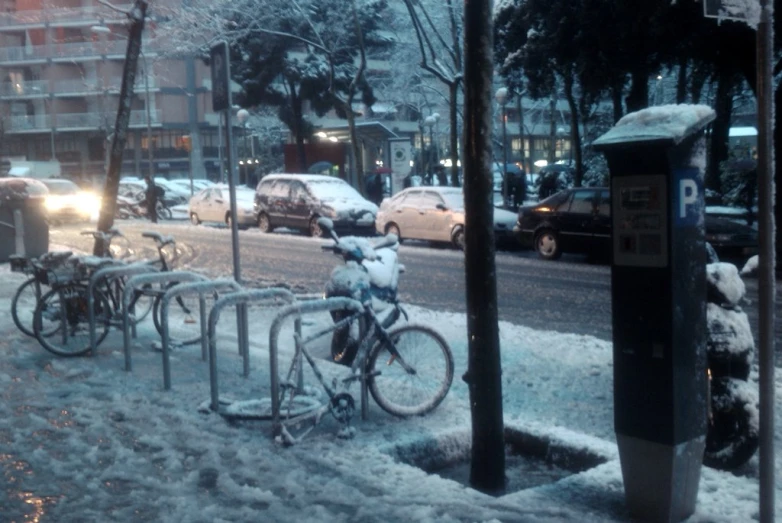 bike racks and cars sit in a snow covered street