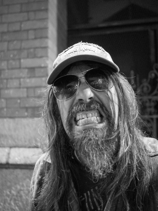 man with long beard in hat and sunglasses sitting outside