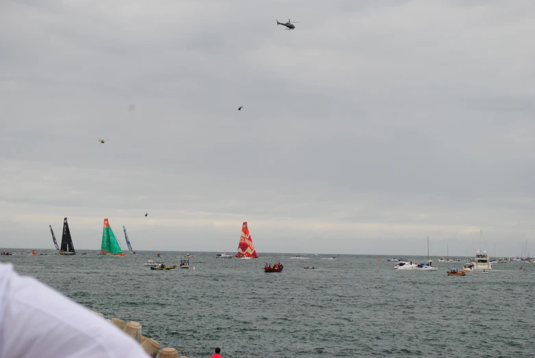 several boats on the ocean and in the background some are flying