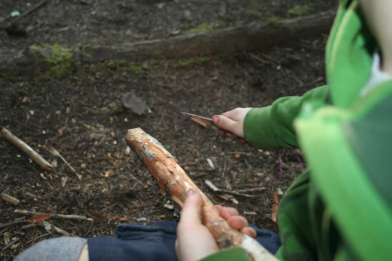 a young child holds onto a nch and twirls a small knife