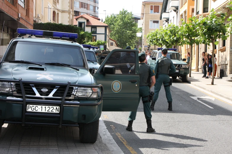 people in uniform walk down a street between several police trucks