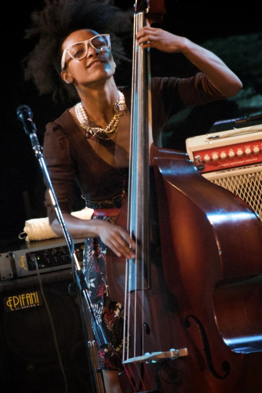 woman with large glasses playing a bass on stage