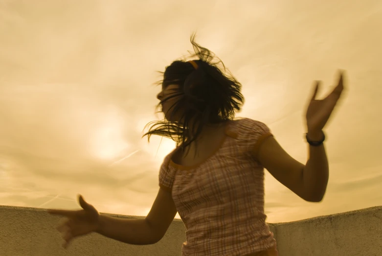 a woman standing in front of the sun throwing her hair back