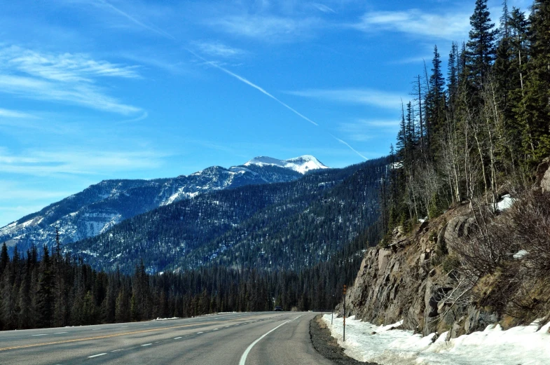 the mountain is covered in snow near a highway