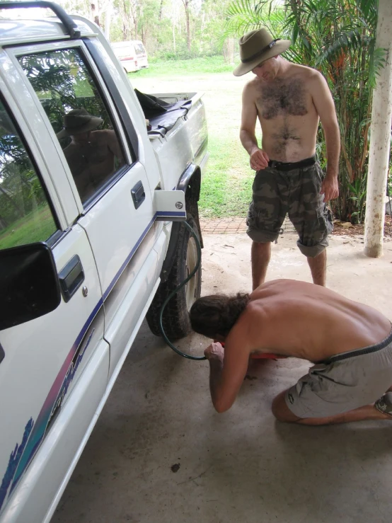 two men that are standing next to a car