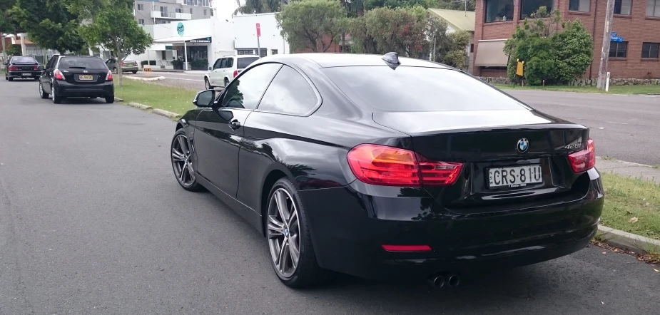 a black bmw parked on the side of a road