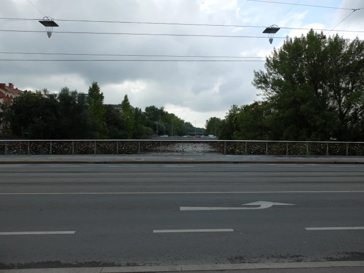 an empty road has a bridge and houses on it