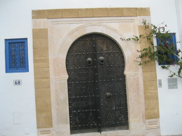 two large black doors with ornate designs are on the side of a building