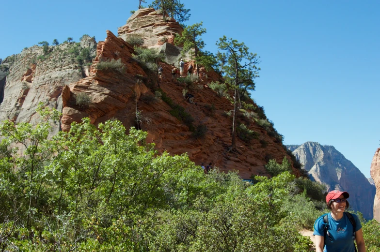 a man walking along the trail up to a very steep mountain