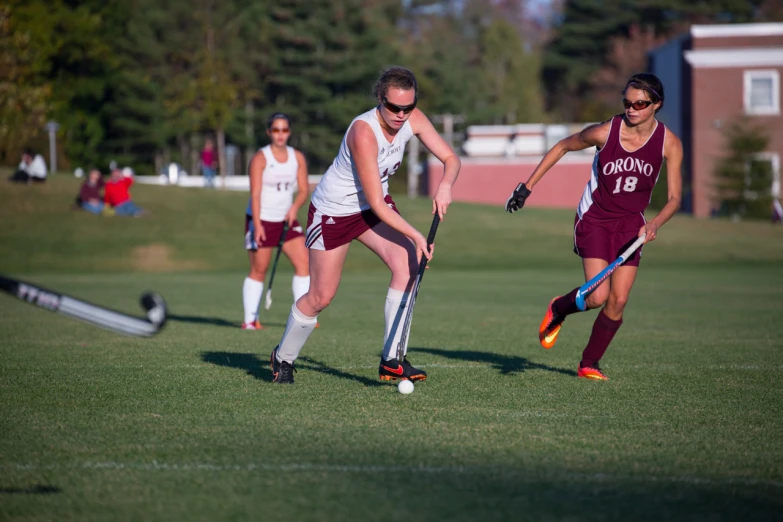 two girls on field playing field hockey