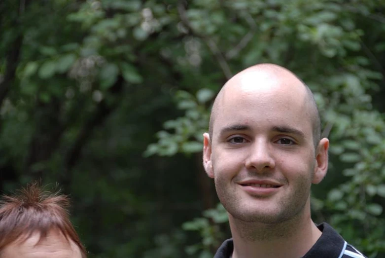 a young man smiling with his hair trimmed to show a bald head