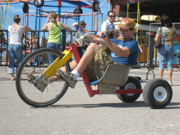 a man is riding a yellow and red tricycle