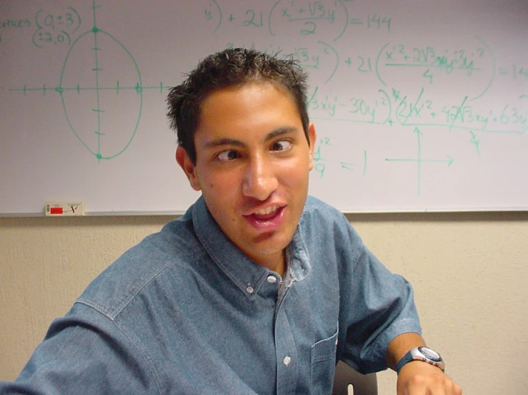 a man with a watch is smiling in front of a white board