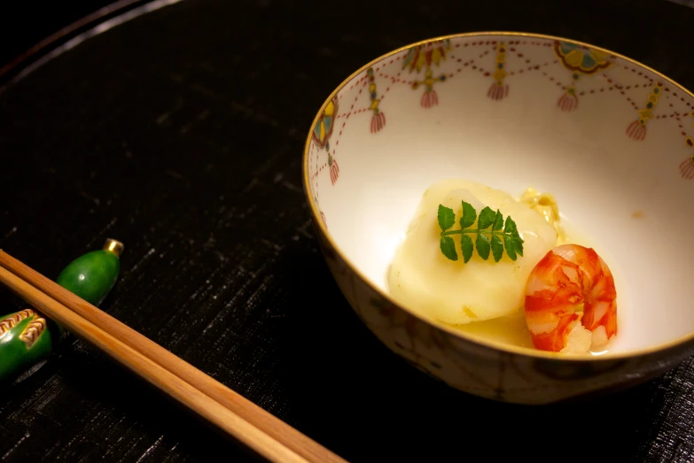 a white bowl filled with food next to two chopsticks