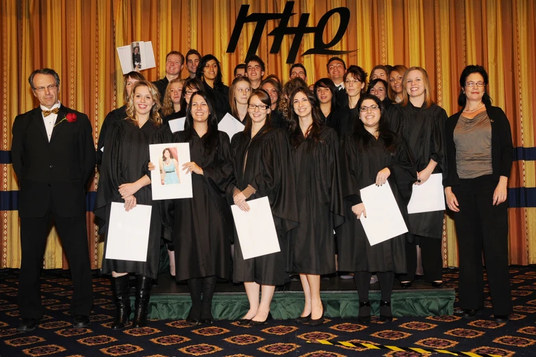 a group of graduates posing in front of yellow curtain