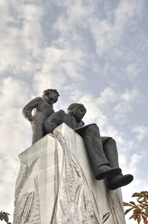 statues sitting on top of a large cement wall