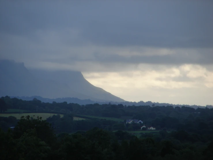 dark clouds over the distant trees near a mountain