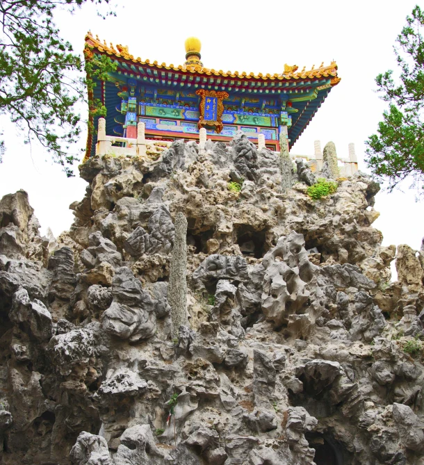 an outdoor building is covered with rocks, trees, and a fountain