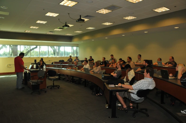 people sitting at the front of a room with desks