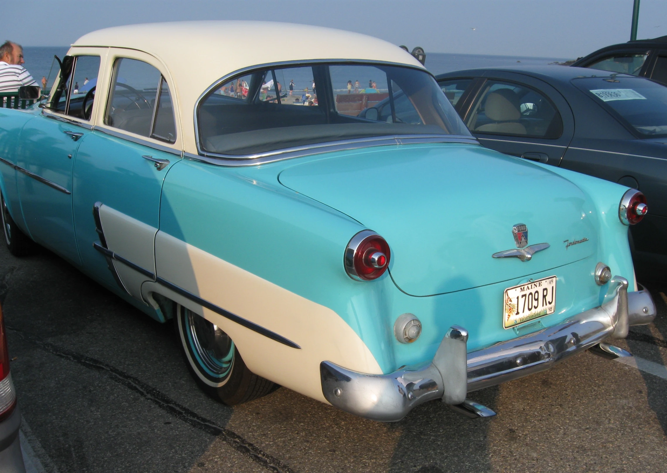 an old blue and white car parked near a bunch of other cars