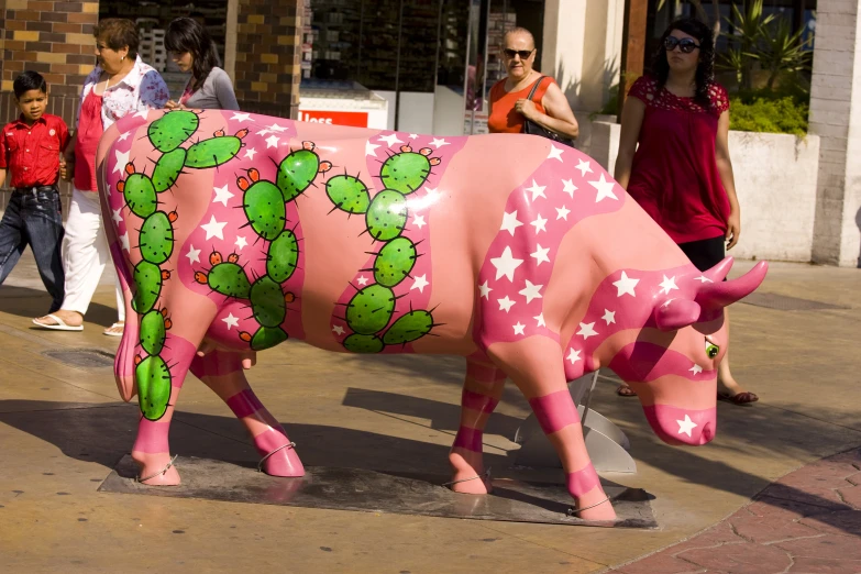 a fake pink cow standing on the side of a road