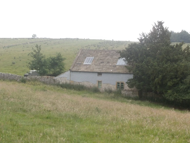 the house is sitting near a pasture on a cloudy day