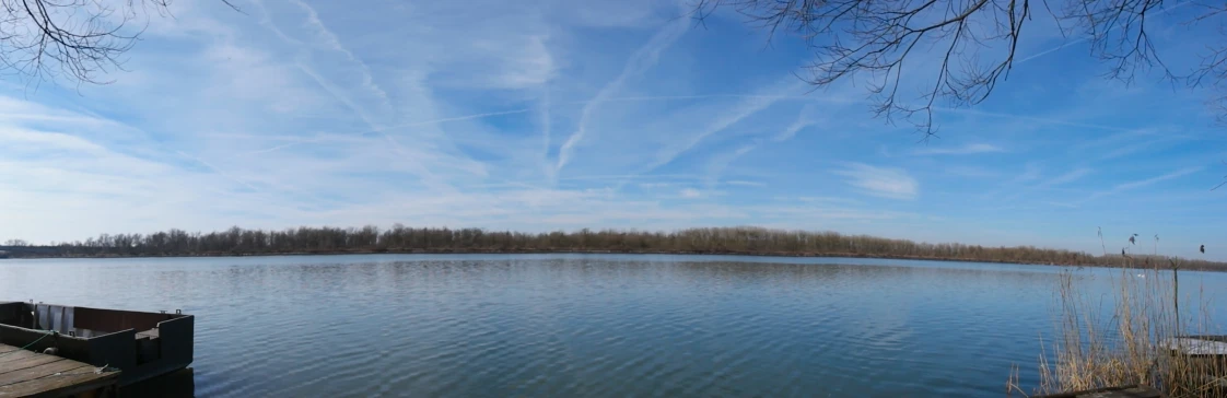 a lake with a dock on the side and a lot of clouds