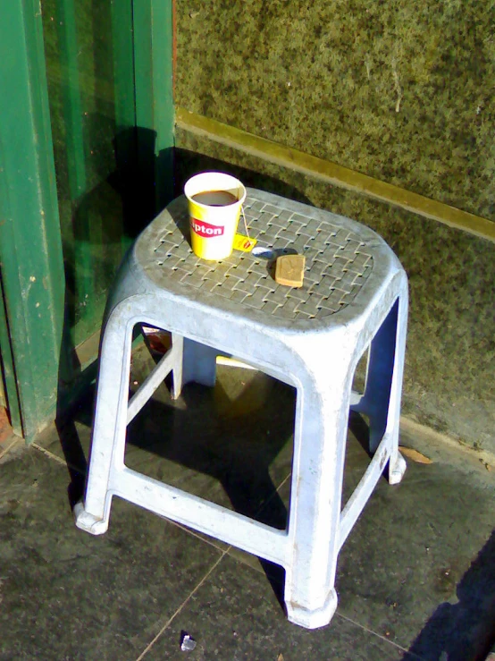 a white stool with an orange cup sitting on it's side