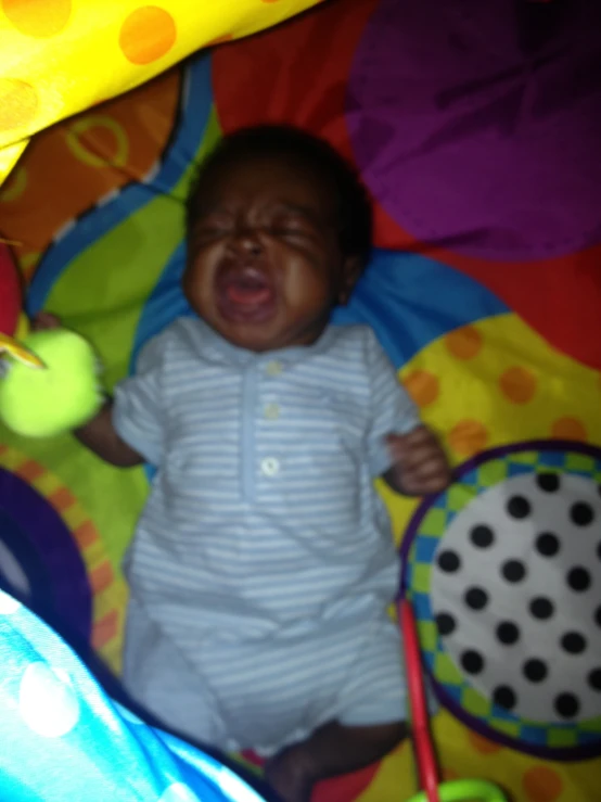 a baby crying while playing with a ball