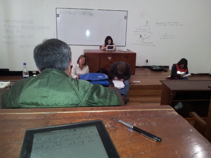 two adults watching a presentation while others sit in front of them