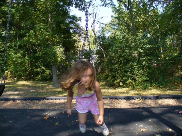 the girl is outside on the swing in the woods