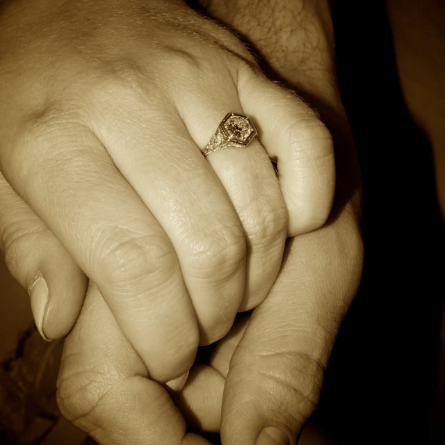 a woman holding a mans hand with a ring on it