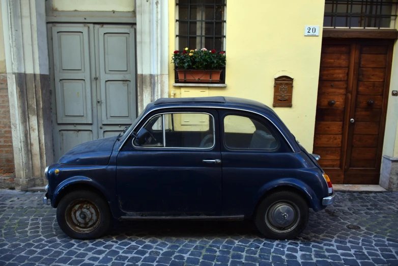 an old small car parked next to a building