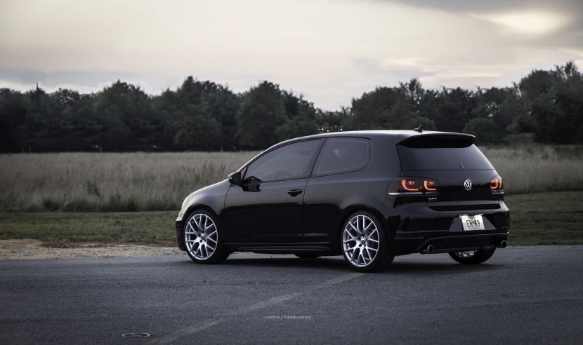 the car is parked near trees with a cloudy sky