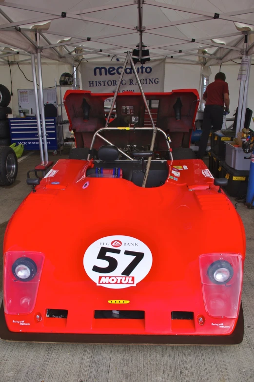 an orange sports car with number 52 parked under a tent