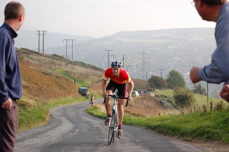 two men on bikes on the road with hills in the background