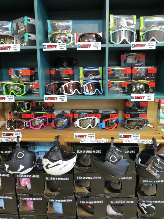 many pairs of ski goggles are lined up on a shelf