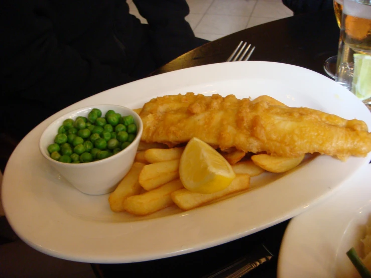 a fish dinner, fries and peas on the side