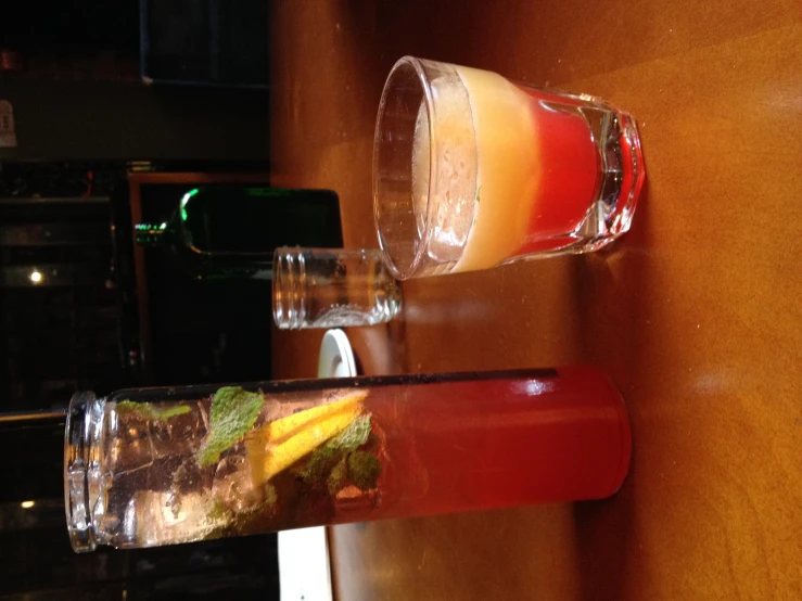 a wooden table with glass cups and bottles filled with drinks