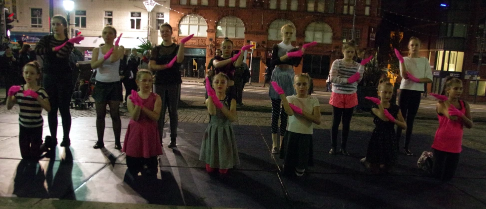 many children with pink ribbon around their neck stand on the street