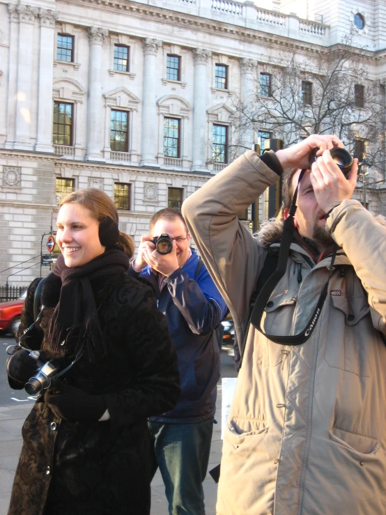 several people standing outside looking at soing while holding up binoculars