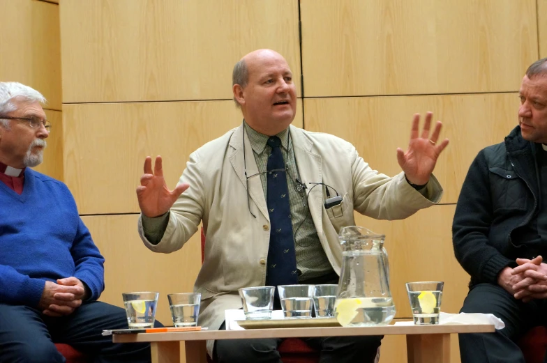 two men and a woman are in discussion on stage