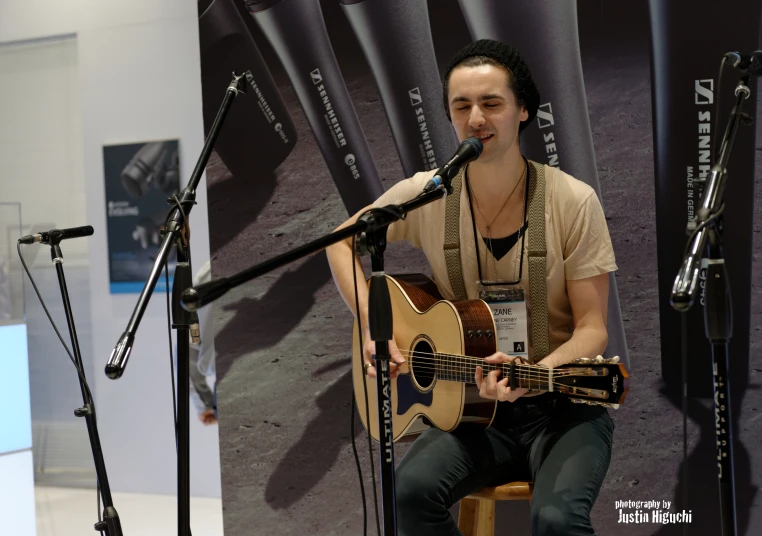 the young man is playing a guitar by a microphone